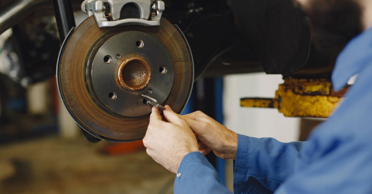 Mechanic working on brake disc in an auto repair workshop, close-up, focus on hands.