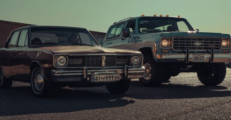 Vintage Dodge Dart and Chevy K5 Blazer cars parked outdoors under clear skies in Iran.