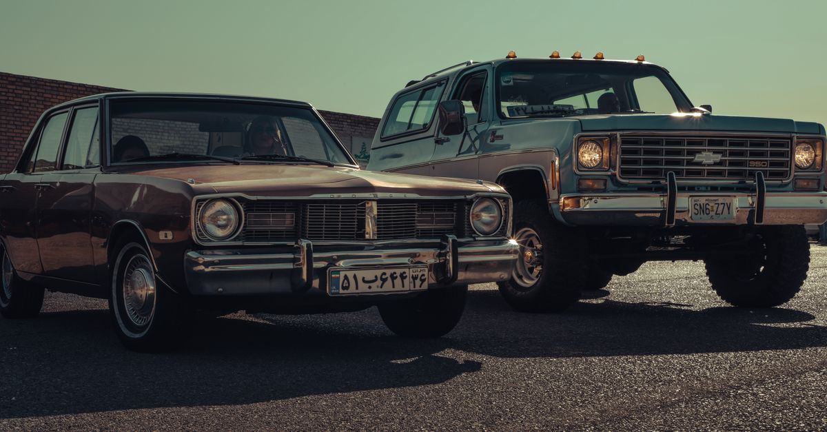 Vintage Dodge Dart and Chevy K5 Blazer cars parked outdoors under clear skies in Iran.