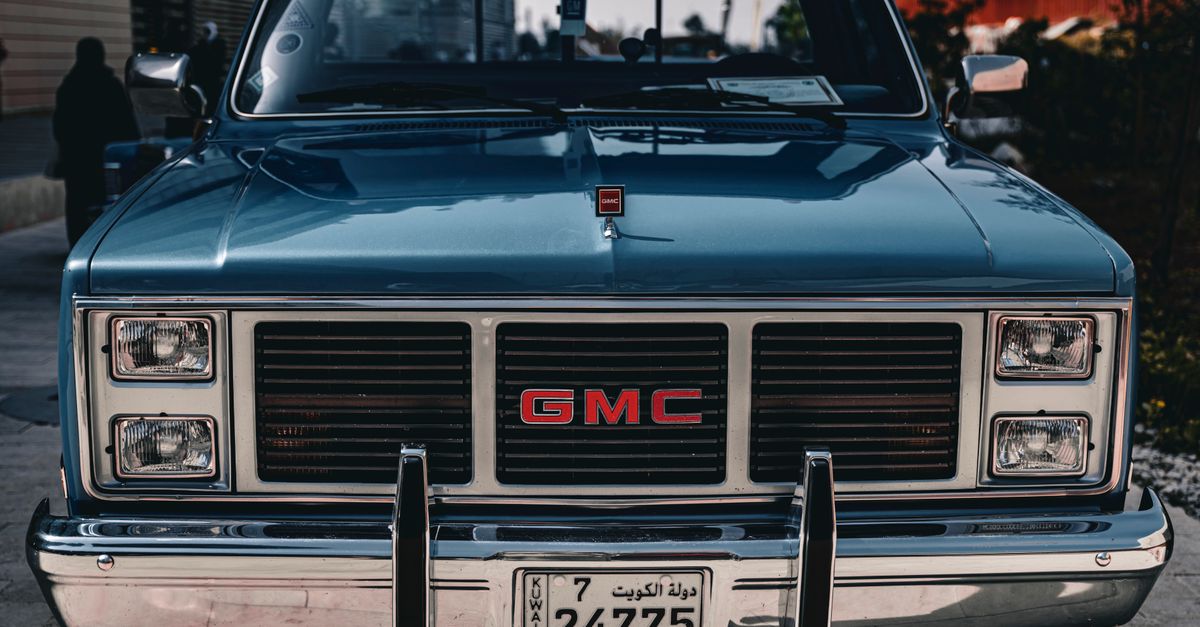 Classic GMC pickup truck with Kuwait license plate in an urban setting.