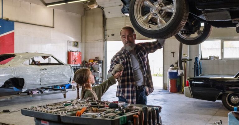 Father and daughter bonding while repairing a car in an auto workshop, symbolizing family togetherness.