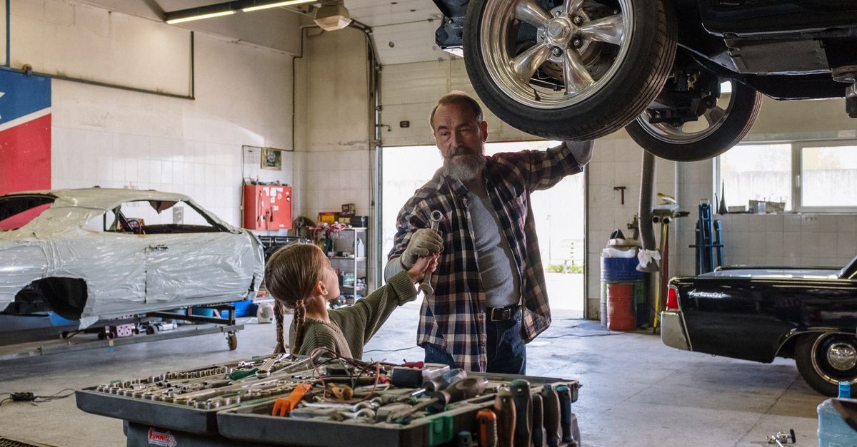 Father and daughter bonding while repairing a car in an auto workshop, symbolizing family togetherness.