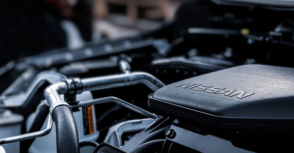 Detailed view of a car engine compartment with visible Nissan branding.