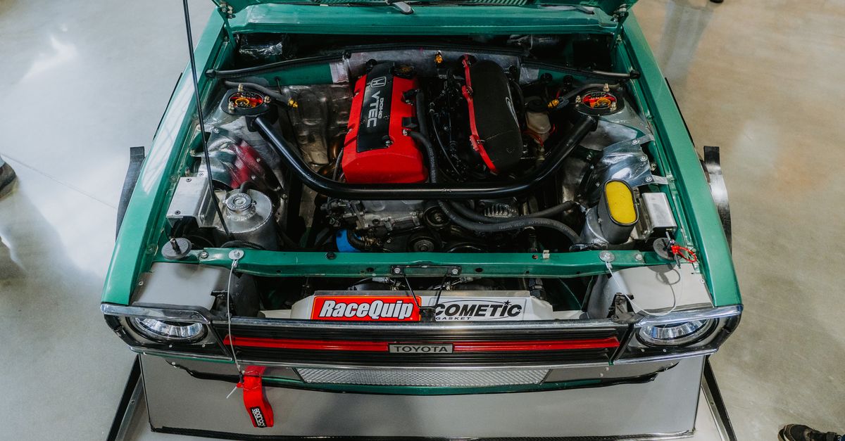 Overhead view of a modified vintage Toyota car engine at a car show.