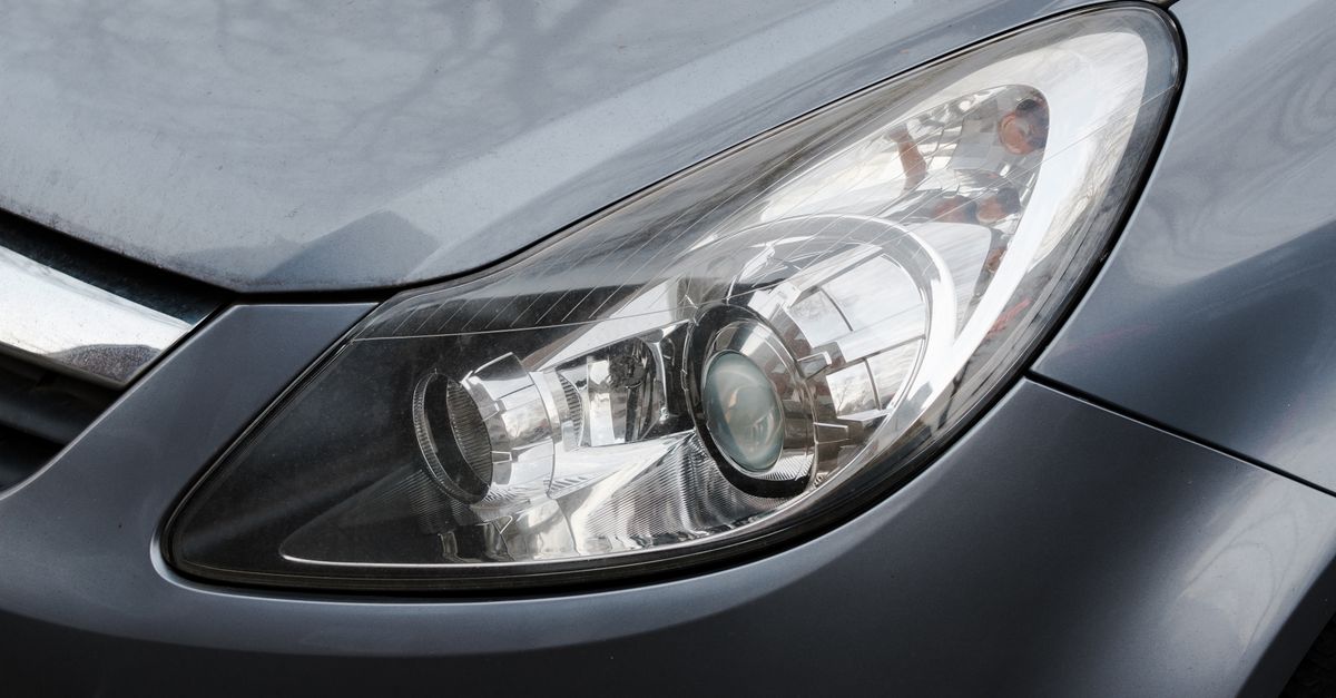 Detailed close-up of a shiny modern car headlight with metallic finish.
