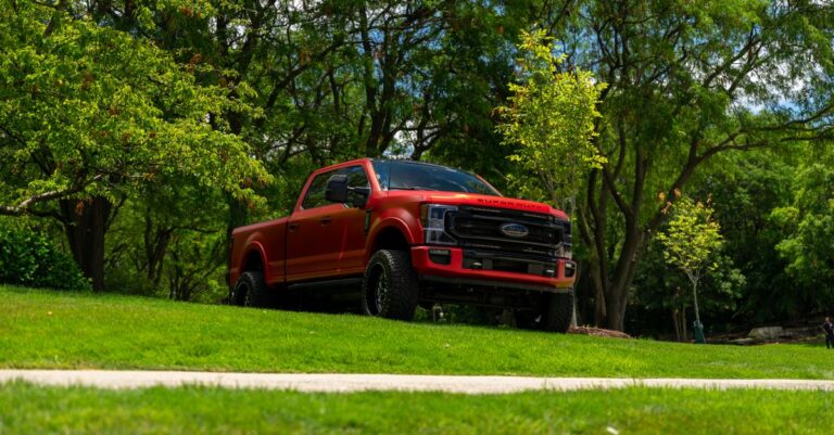 A red pickup truck stands parked amidst lush greenery, capturing a serene outdoor scene in Illinois.