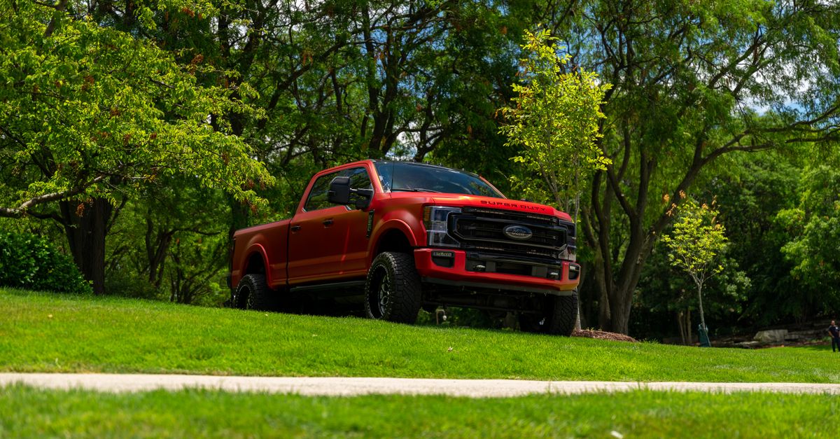 A red pickup truck stands parked amidst lush greenery, capturing a serene outdoor scene in Illinois.