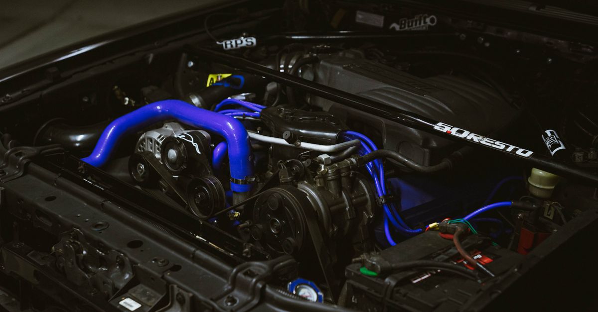 Detailed view of a car engine featuring vibrant blue pipes and machinery components.