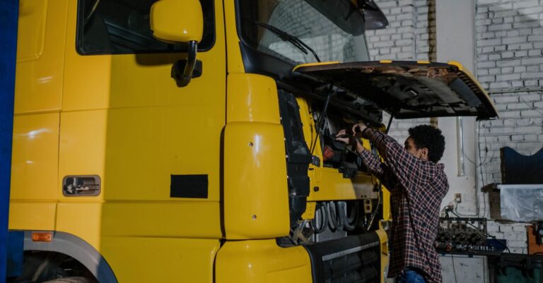 A mechanic working on a truck engine in an indoor mechanical workshop.