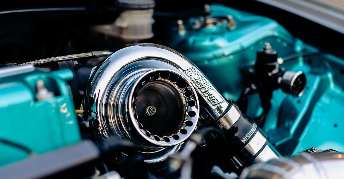 Detailed photo of a car turbocharger in a polished engine bay with chrome elements.