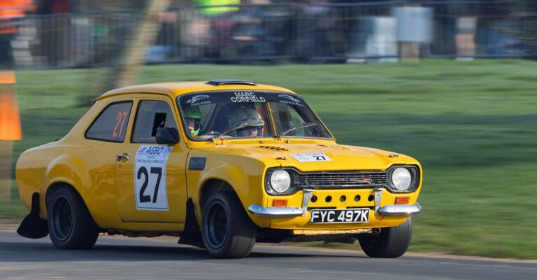 Yellow Ford Escort rally car in action at Weston Park during a motorsport event.