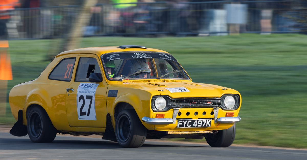 Yellow Ford Escort rally car in action at Weston Park during a motorsport event.