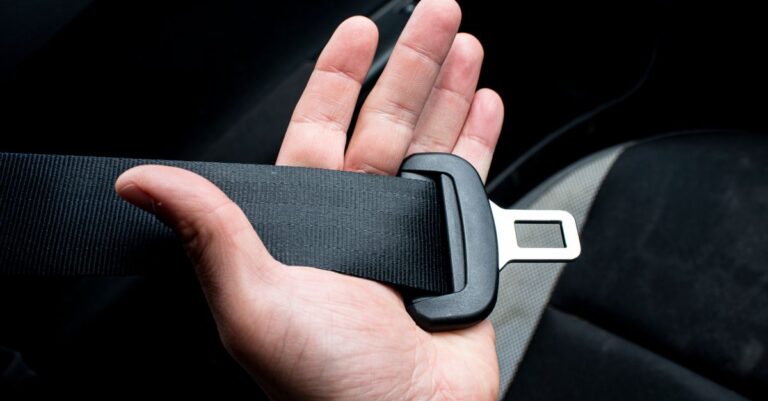 Close-up of a hand holding a car seat belt for safety and security.