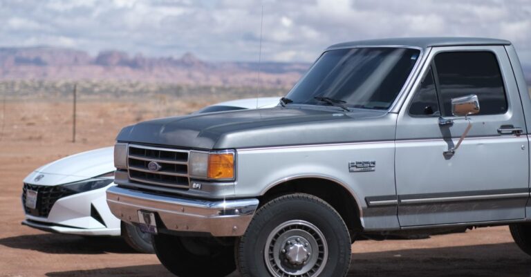 Classic Ford truck and modern car in a serene desert backdrop on a sunny day.