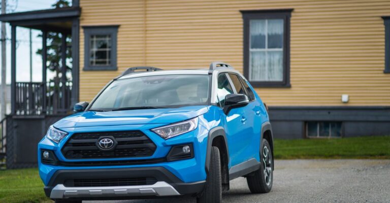 Blue Toyota RAV4 parked outside a house, showcasing modern SUV design.